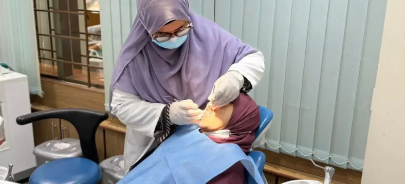 Dr. Tasmia performing dental procedure on patient in chair using professional equipment